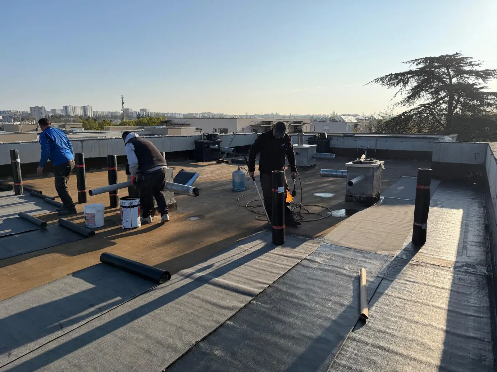 Pose d'une membrane d'étanchéité bitumineuse au chalumeau sur une toiture-terrasse d'immeuble par Muller Toiture, étanchéité dans l'Est lyonnais